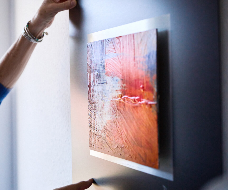 Frau rückt Bild an der Wand in der Klinik Wollmarshöhe zurecht